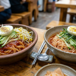 Jjolmyeon and bibim guksu served side by side on a snack-bar table